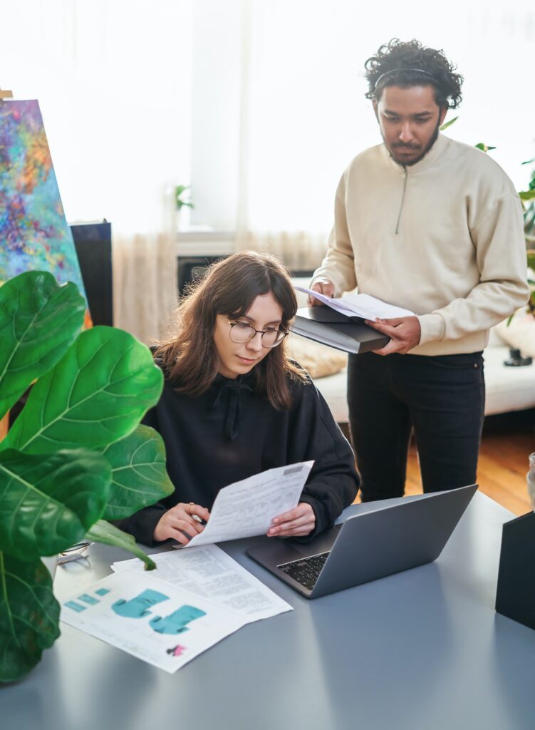 Female worker and her indian coworker doing their work in sunny room