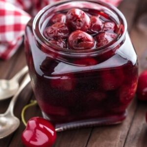 Berries cherry with syrup in a glass jar. Canned fruit